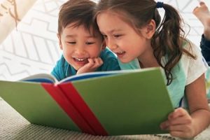 Photo of two children reading a book 